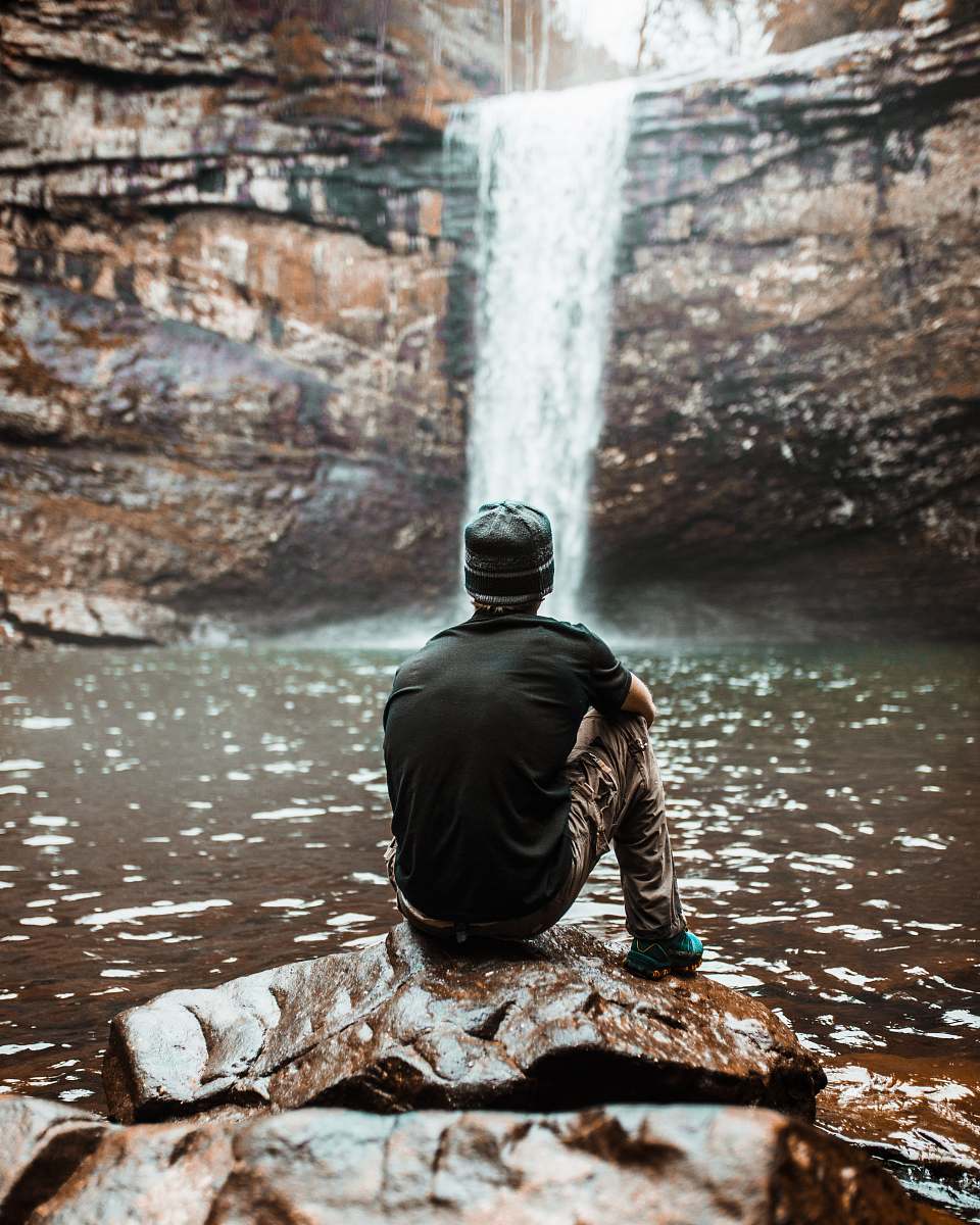 lookout mountain man sitting on brown rock near waterfalls at day time man